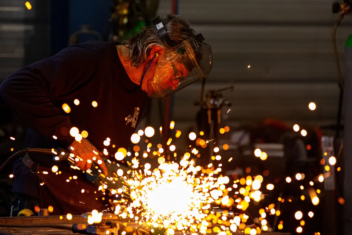 Welder in a protective mask cutting metal with sparks flying